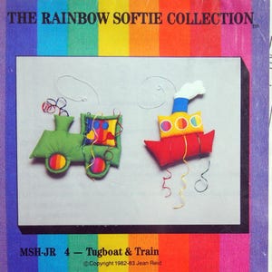 May include: A craft pattern featuring a green train and a red tugboat, both with colorful accents. The text "THE RAINBOW SOFTIE COLLECTION" is at the top. The pattern is titled "Tugboat & Train" and copyrighted 1982-83.