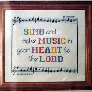 May include: A framed cross-stitch with the text "SING and make MUSIC in your HEART to the LORD" in colorful letters. The text is surrounded by musical notes and the words "BEETHOVEN" and "EPHESIANS 5:19".