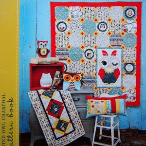 May include: An assortment of owl-themed textiles, including a quilt, cushion, and table runner. The quilt has a red border and circular owl patterns. The cushion features a patchwork design with heart and floral details. A small owl ornament is also visible.