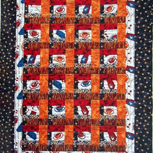 May include: A quilt with a chequered pattern featuring coffee cups and text about different types of coffee. The quilt is framed with a black fabric with gold stars and a brown fabric with coffee beans.