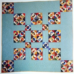 May include: A quilt with a blue background and a pattern of colourful squares. The squares are arranged in a grid pattern and each square has a different design. The quilt is made of fabric scraps and is a great example of patchwork quilting.