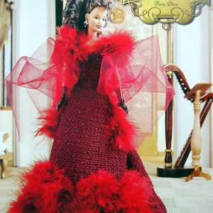 May include: A doll in a red crocheted party dress with a feathered hem and boa. The doll has dark hair and earrings. The image includes the text "The Southern Belle Collection Party Dress".