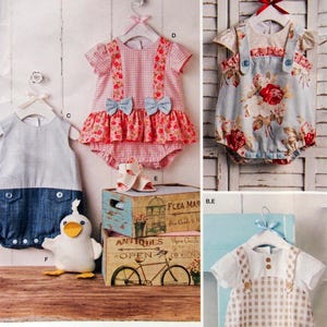 May include: Three baby outfits with different patterns and styles. The first outfit is a pink and white gingham romper with a floral print and a blue bow. The second outfit is a blue floral romper with a denim bib and white straps. The third outfit is a white and brown gingham romper with a white top and brown straps.