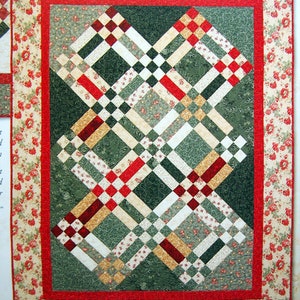 May include: A quilt with a red, white, and green plaid pattern. The quilt is framed with a floral border.