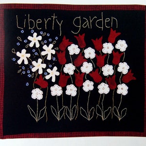 May include: A black fabric wall hanging with red and white embroidered flowers and the text "Liberty Garden".