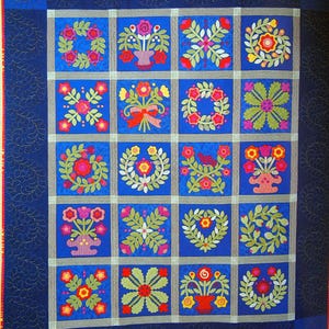 May include: A vibrant quilt with a blue background and a grid of floral designs. Each square features a unique arrangement of flowers in red, yellow, and green, set against a blue backdrop. The quilt is bordered with a darker blue fabric.