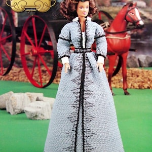 May include: A doll in a light blue crocheted dress with black trim, standing in front of a red horse and carriage. The doll has brown hair and is wearing a black hat. The text "The Southern Belle Collection Carriage Ride" is in the upper left corner.