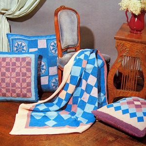 May include: A blue and pink knitted throw blanket with a checkered pattern, along with three matching pillows. The throw is draped over a chair with a blue velvet cushion.