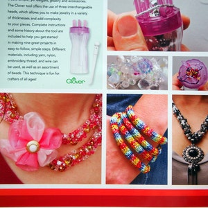 May include: A book cover for a jewelry making craft book titled "Design Originals" with a close-up of a purple Clover French Knitter tool. The book cover also features several examples of jewelry made with the tool, including a necklace with a pink flower, a bracelet with colorful beads, and a necklace with black beads.