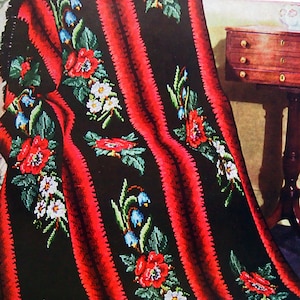 May include: A black and red crocheted throw blanket with a floral pattern. The blanket features red poppies, white flowers, and blue bells.