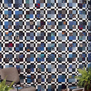 Peut inclure: Une grande courtepointe faite à la main avec un motif patchwork. La courtepointe présente un motif de grille de carrés noirs et blancs, chaque carré contenant de plus petits carrés de divers tissus bleus. La courtepointe est exposée sur un mur.