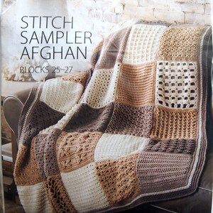 May include: A crocheted afghan in a patchwork design, featuring squares in shades of brown, beige, and cream. The afghan is draped over a chair. The text on the cover reads "STITCH SAMPLER AFGHAN" and "BLOCKS 25-27".