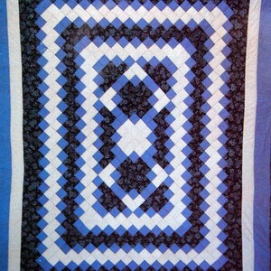 Peut inclure: Une courtepointe avec un motif de diamants noirs, blancs et bleus. Les diamants sont disposés en un motif de cercle concentrique.