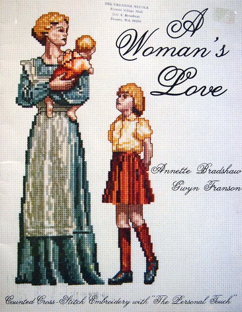 Puede incluir: Un patr&oacute;n de bordado de punto de cruz contado que representa a una mujer sosteniendo a un ni&ntilde;o y una ni&ntilde;a de pie a su lado. El dise&ntilde;o se titula "A Woman's Love" e incluye los nombres Annette Bradshaw y Gwyn Franson. El patr&oacute;n se describe como "Bordado de punto de cruz contado con "The Personal Touch."