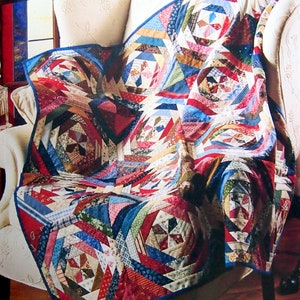 May include: A vibrant quilt with a complex geometric pattern, draped over a white armchair. The quilt's design incorporates red, blue, and cream hues. The textile features circular and angular shapes, creating a visually rich and detailed piece.