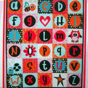May include: A colorful alphabet quilt with letters A through Z, each in a unique square. The quilt features various patterns, including polka dots, flowers, and stars, with a red border. Decorative elements include a bee, heart, and owl.