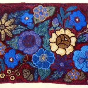 May include: A rectangular rug with a floral design. The rug has a deep burgundy background with various flowers in shades of blue, tan, and cream. The flowers are arranged in a dense pattern, with green leaves and stems. The rug is likely made of wool or a similar material.