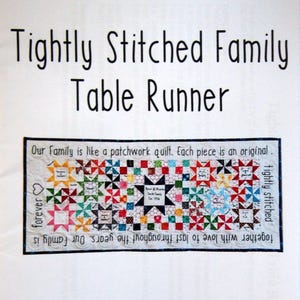 May include: A white fabric table runner with the text "Tightly Stitched Family Table Runner" at the top. The runner features a colourful patchwork quilt design with the text "Our Family is like a patchwork quilt. Each piece is an original. Together with love to last throughout the years. Our Family is forever tightly stitched" in black text.