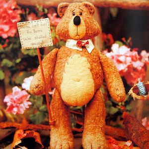 Könnte beinhalten: Ein handgefertigter brauner Teddybär hält ein Schild mit der Aufschrift "Please don't feed the Bears We're stuffed already!". Der Bär hat einen weißen Kragen, eine rote Fliege und einen cremefarbenen Bauch.