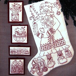 May include: A white Christmas stocking and four framed embroidered images. The stocking features a Santa Claus design with a bag of gifts. The framed images depict a snowman, a boat with animals, a train, and a house, all in a red embroidered style.