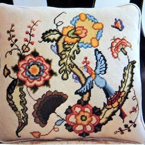 May include: A white pillow with a colorful floral embroidery design. The design features a variety of flowers, leaves, and a bird in shades of blue, red, yellow, green, and brown.