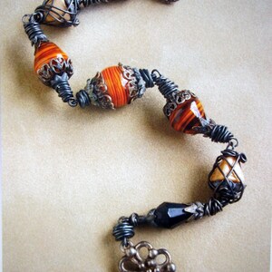 May include: A black and brown wire-wrapped necklace with various beads, including a flower charm.