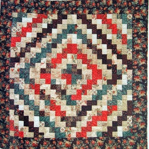 May include: A quilt with a geometric pattern of red, black, white, and green squares. The quilt is surrounded by a border of dark brown fabric with a floral pattern.