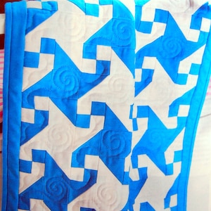 May include: A blue and white quilt with a star pattern. The quilt is made of fabric squares sewn together to create a geometric design.