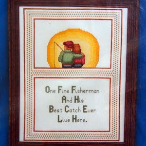 May include: Cross-stitch pattern featuring a couple fishing with the text "One Fine Fisherman And His Best Catch Ever Live Here."