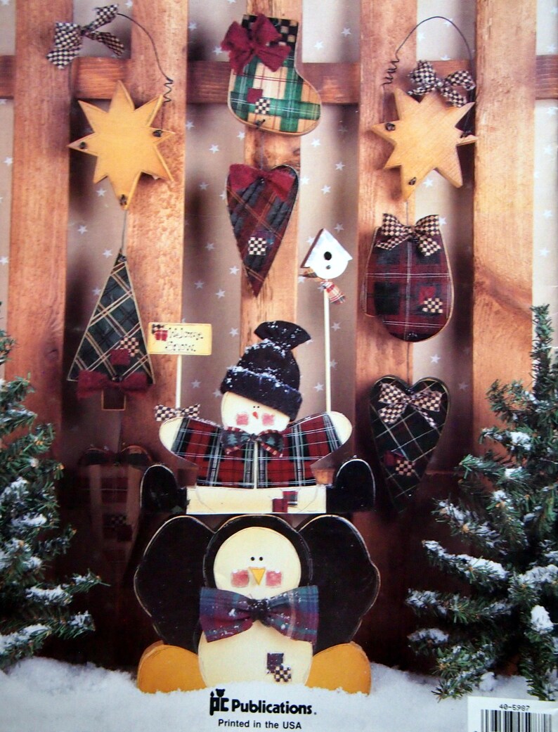 Puede incluir: Una colecci&oacute;n de adornos navide&ntilde;os de madera, que incluyen una estrella, un &aacute;rbol, un calcet&iacute;n, un coraz&oacute;n y un mu&ntilde;eco de nieve, todos adornados con patrones de cuadros escoceses y lazos. Tambi&eacute;n se presenta un adorno de ping&uuml;ino. Los adornos est&aacute;n dispuestos sobre un fondo de madera.