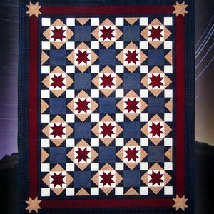 May include: A quilted blanket with a repeating star pattern. The design features alternating squares of navy blue and tan, with white and burgundy star-shaped accents. A burgundy border frames the central design, with tan star corner accents.