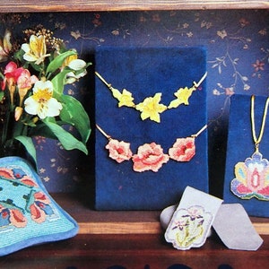 May include: A display of four embroidered floral designs. A blue pillow with a floral pattern, a yellow floral necklace, a pink floral necklace, and a multi-colored floral pendant.