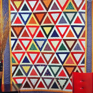 May include: A colorful quilt made of fabric scraps in a variety of patterns and colors. The quilt is made up of a series of triangles, with each triangle having a different pattern. The quilt is framed with a blue and yellow border.