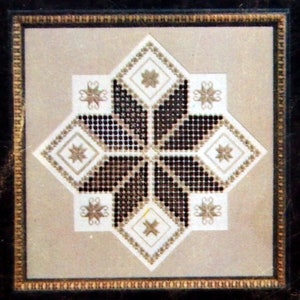 May include: A framed embroidery design featuring a black and white geometric star pattern with a white background. The star is surrounded by a white border and the frame has a gold trim.
