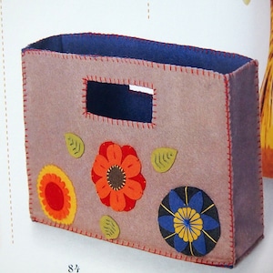May include: A grey felt storage box with a blue felt lining and a cut-out handle. The box is decorated with felt appliques of flowers in red, orange, yellow, blue, and green.