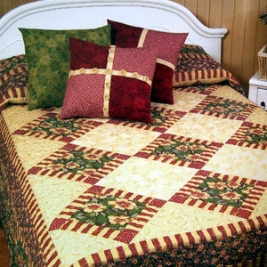 May include: A white bed with a cream, green, and red patterned quilt. The bed has a white headboard and is decorated with three pillows. The pillows are green, red, and white with a floral pattern.