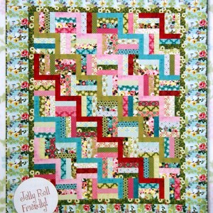 May include: A patchwork quilt in shades of pink, red, green, and blue. The quilt's design is made up of rectangular blocks. It measures 193 x 234 cm and has a floral border. The text "Jelly Roll Friendly!" is in a white circle.