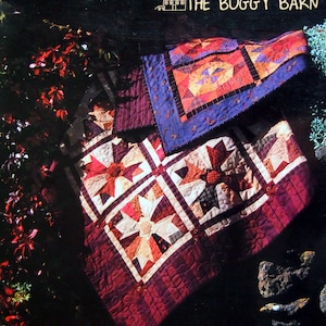 May include: A quilt pattern book titled "That Crazy Thing We Do" by The Buggy Barn. The book cover features a photo of a quilt with a red, white, and blue star pattern.