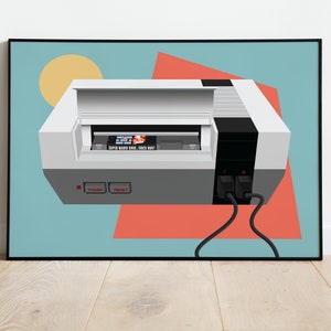 May include: Framed art print featuring a stylized illustration of a classic video game console. The console is white and gray, with a black section and two controller ports. The game cartridge reads "SUPER MARIO BROS. / DUCK HUNT". The background is light blue with geometric shapes.