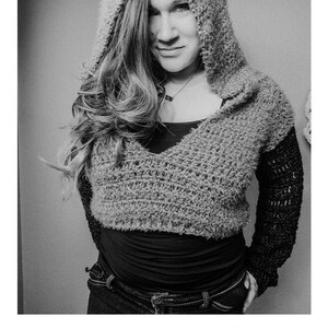May include: A black and white photo of a person wearing a gray crocheted hoodie with a black crocheted sleeve. The hoodie has a V-neck and is cropped. The person is wearing jeans and has their hands in their pockets. The text "HARMONY HOODIE" is below the image, and the text "crochet pattern" and "serendipity-as-always.com" are below that.