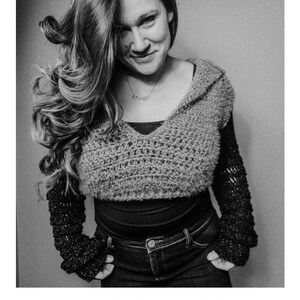 May include: A black and white photo of a person wearing a crocheted hooded top with long sleeves. The top is a cropped style and the sleeves are long and loose. The person is wearing jeans and has their hands in their pockets. The text "HARMONY HOODIE" is below the image, and the text "crochet pattern" and "serendipity-as-always.com" are below that.