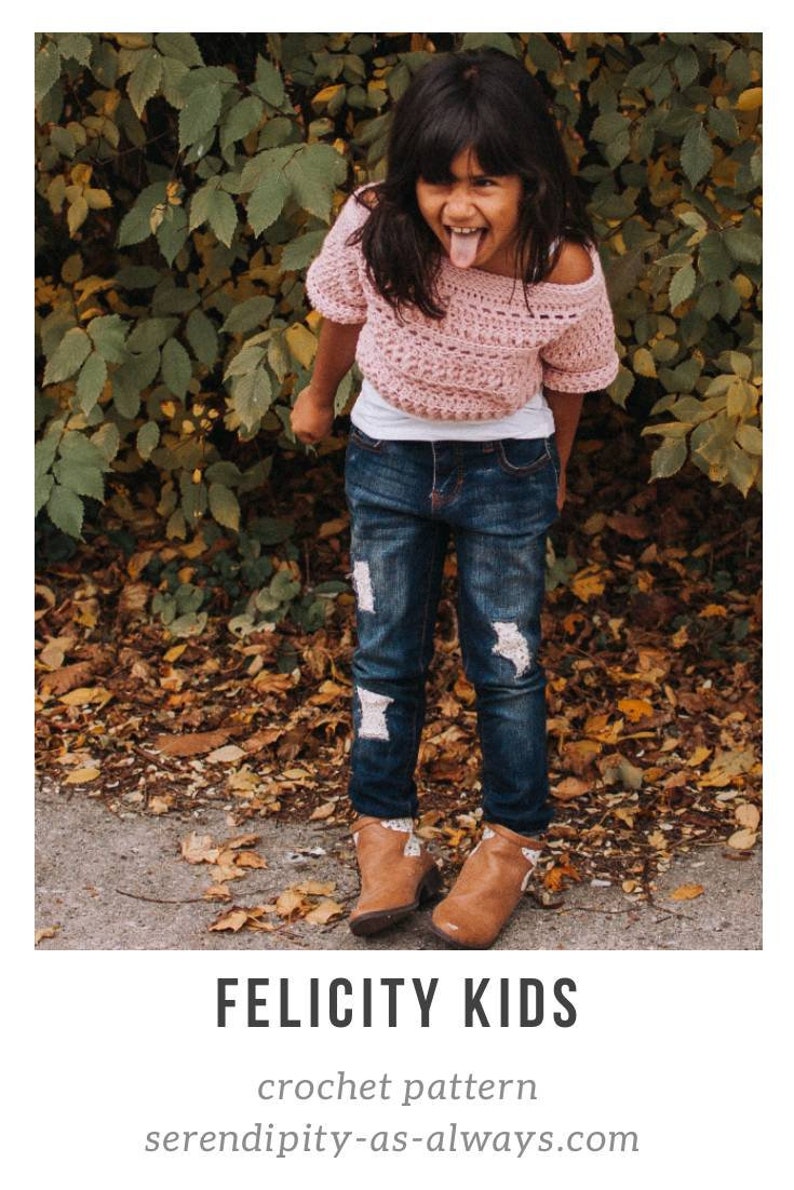 May include: A young girl wearing a pink crochet top with white crochet trim, blue jeans with distressed details, and brown ankle boots. The girl is standing in front of a leafy background and is sticking her tongue out.