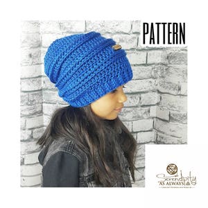 May include: A blue crocheted beanie with a brown leather label. The beanie is slouchy and has a ribbed texture. The beanie is being worn by a person with long dark hair.