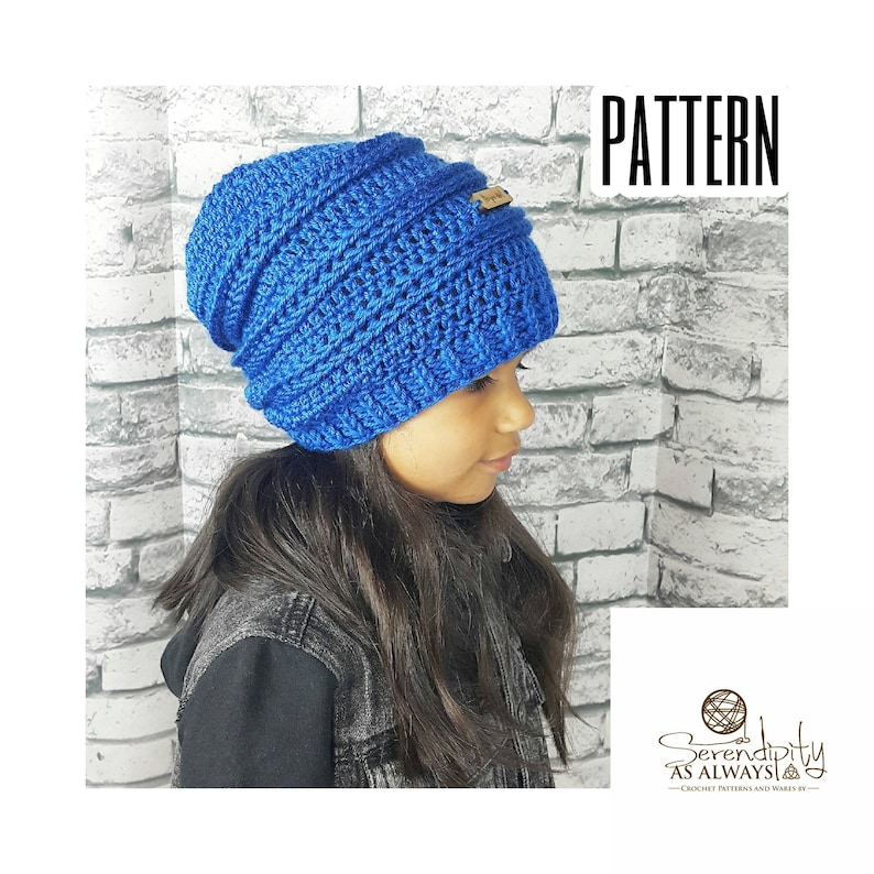 May include: A blue crocheted beanie with a brown leather label. The beanie is slouchy and has a ribbed texture. The beanie is being worn by a person with long dark hair.
