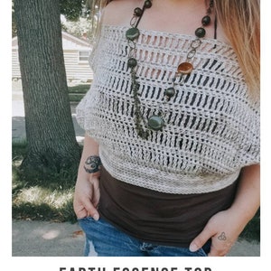 May include: A crochet top with an off-the-shoulder design, featuring a light beige color and a delicate openwork pattern. The top is paired with a brown tank top and blue jeans. The image includes the text "EARTH ESSENCE TOP crochet pattern serendipity-as-always.com".