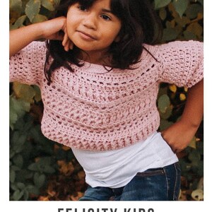 May include: A pink crochet top with a lacy pattern. The top is cropped and has short sleeves. The model is wearing the top with a white t-shirt and blue jeans. Felicity Kids crochet pattern serendipity-as-always.com