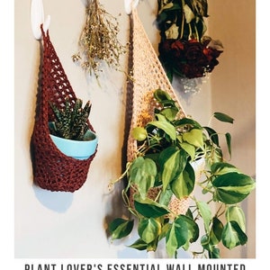 Puede incluir: Dos maceteros colgantes de crochet en marr&oacute;n y beige cuelgan de ganchos blancos en una pared. Los maceteros est&aacute;n llenos de plantas en maceta. El texto "PLANT LOVER'S ESSENTIAL WALL MOUNTED PLANT HOLDER crochet pattern  serendipityasalways.com" est&aacute; en la parte inferior de la imagen.