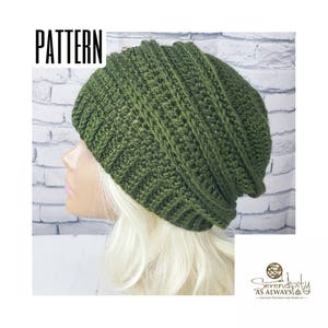 Puede incluir: Un gorro de punto de color verde con un patrón de puntada texturizado. El gorro es holgado y tiene un borde doblado.