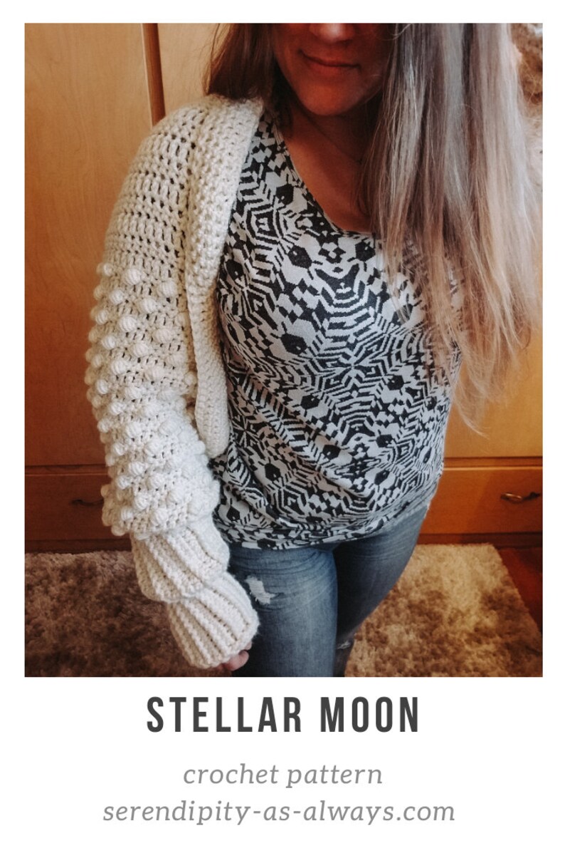Op de afbeelding: Een close-up van een vrouw die een wit gebreid vest draagt met een textuur, bobbelsteekpatroon. Het vest heeft lange mouwen en is getailleerd. De vrouw draagt ook een zwart-wit geprint shirt en een blauwe jeans. De tekst "STELLAR MOON crochet pattern serendipity-as-always.com" is zichtbaar onderaan de afbeelding.