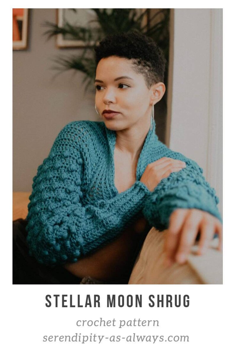 Op de afbeelding: Een tealblauwe gehaakte sjaal met een textuurpatroon. De sjaal wordt gedragen door een persoon met kort haar en is gestyled met een casual, ontspannen look. De tekst "STELLAR MOON SHRUG" en "crochet pattern" is zichtbaar onder de afbeelding. Het websiteadres "serendipity-as-always.com" is ook zichtbaar.